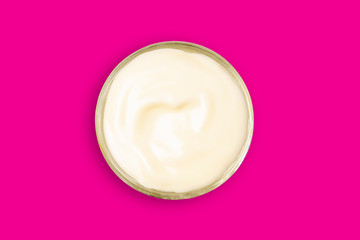 Spa cream in a glass cup placed on a Pink background. Cosmetic cream camomile. Organic cosmetics with coconut on Isolated Pink or Magenta background top view.