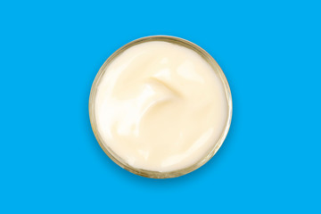 Spa cream in a glass cup placed on a blue background. Cosmetic cream camomile. Organic cosmetics with coconut on blue background top view.