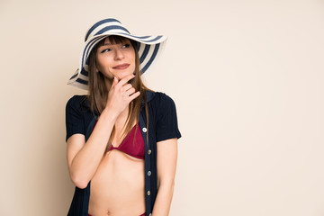 Woman in bikini on ocher background thinking an idea