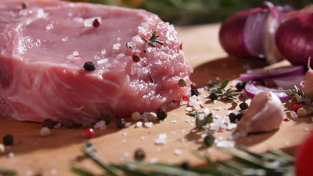 Close-up slow motion footage of strewing salt and pepper at fresh raw beef meat on the desk