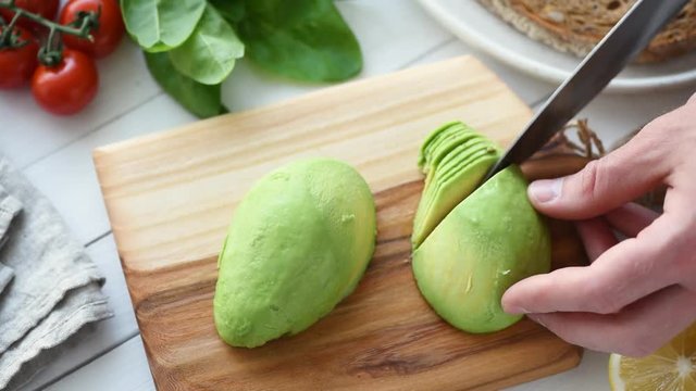 Male hands slicing avocado, home cooking process