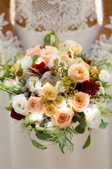 Luxurious bouquet of beige, cream and red roses with snow-white freesia in the hands of an unrecognizable bride