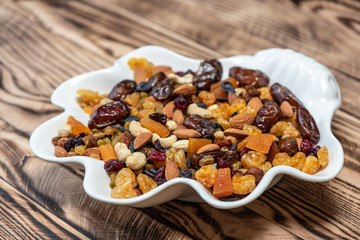 Plate of dried fruits on wooden table, Mix of nuts and berries: raisins, hazelnut, cashews, almonds, yellow, cranberries, dried dates and apricots