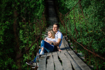 happy couple  kissing on a wooden bridge.A love story. A man and a woman near the bridge. Love relationship. Happy smiling, dreaming couple together outdoor.romantic date in the green park.