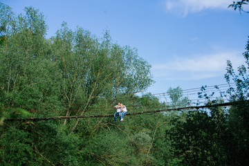  loving man and woman is sitting on the bridge.Hugging couple smiling and looking at each other outdoor in the spring.