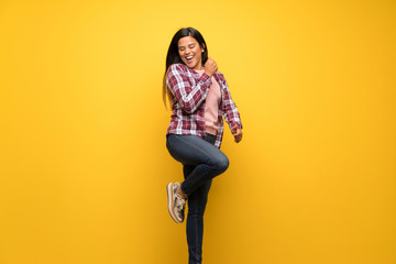 Fototapeta na wymiar Young Colombian girl over yellow wall jumping