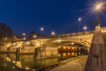 Fototapeta na wymiar Ponte Sisto bridge and river Tiber at night at the side of the stairs. A stone street bridge in the historic center of Rome at night with illumination. Path at the riverside with lateral view