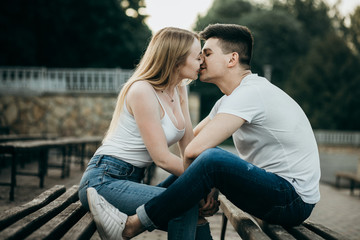 A young couple in love kissing on the bench in the park