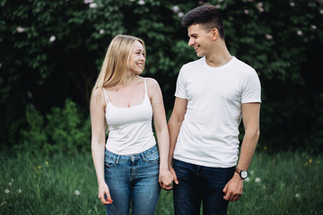 Obraz premium A young couple in love holding hands and laughing in front of a flowering bush