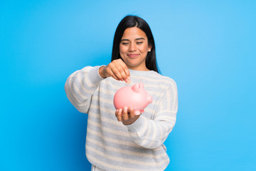 Young Colombian girl with sweater taking a piggy bank and happy because it is full