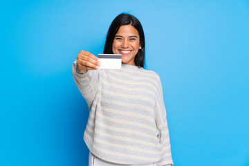 Young Colombian girl with sweater holding a credit card