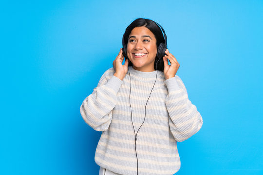 Young Colombian Girl With Sweater Listening To Music With Headphones