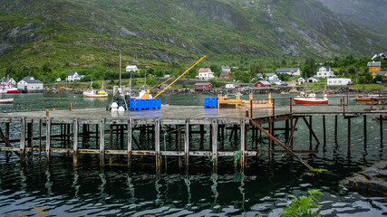 Fototapeta na wymiar Village on the fjord with a pier in Norway. Cloudy day
