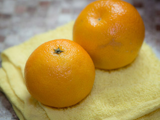 Two whole tangerines lying on a kitchen towel