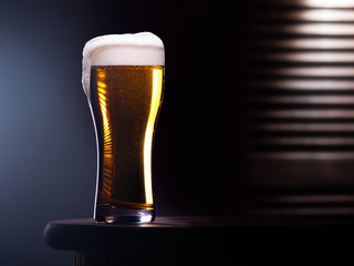 Glass of light beer on wooden table with wooden background