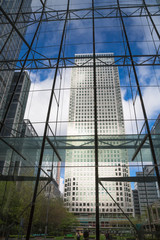 London, UK. Glass windows of the ground floor office building with beautiful reflections and  view on Canary Wharf tower