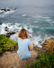 Girl watching waves from cliff