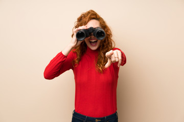 Redhead woman with turtleneck sweater with black binoculars