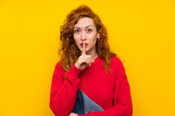 Redhead woman with overalls over isolated yellow wall doing silence gesture