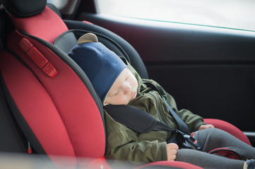 Close Up caucasian cute baby boy sleeping in modern car seat. Child traveling safety on the road....