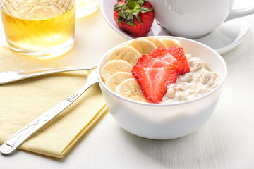Bowl of breakfast muesli decorated with banana, strawberry slices and chia seed