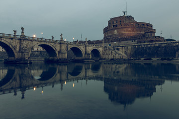 River Tiber with the Aurelius bridge over waters with Castel Sant Angelo at dusk. Reflections of...