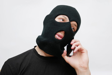 Thug in black mask talking on the phone. Receiving orders. Crime Informing.