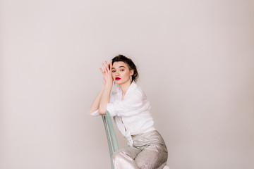 serious beautiful woman sitting on chair isolated on grey