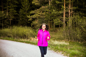 Young woman enjoys a healthy way of life while running the road on the mountain.Concept-Healthy way of life