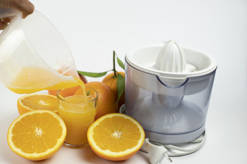 Juicer with freshly squeezed orange juice and whole and sliced oranges