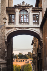 Fototapeta na wymiar Passage under an old bridge between two buildings in Rome
