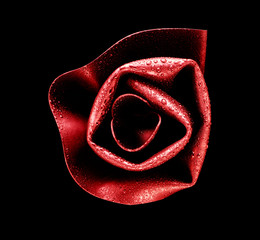 Plastic red rose covered with dew, on black background