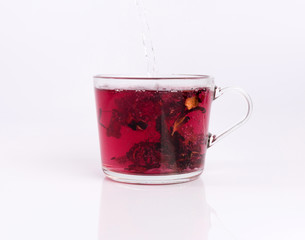 Pouring hot water to the glass cup with hibiscus tea, isolated on white background