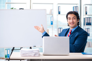Naklejka premium Young handsome businessman in front of whiteboard 
