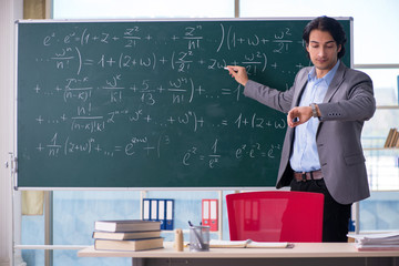 Young handsome math teacher in classroom 