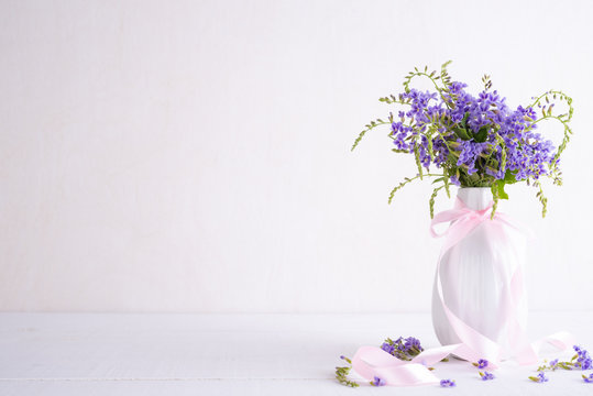 lovely purple flower in vase on white wooden table.