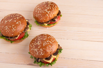 sesame buns and cheeseburgers with mushrooms on wooden table, place for text 