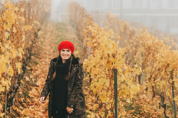 Fototapeta na wymiar Young woman hiking in Lavaux vineyards in autumn, wearing warm military jacket and red beret