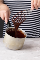 profesional cooker mixes chocolate cream and eggs by whisk for dessert