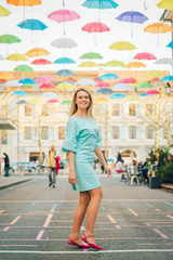 Outdoor portrait of beautiful happy woman with blond hair, wearing turquoise dress, looking back over the shoulder. Image taken in Carouge, Geneva, Switzerland