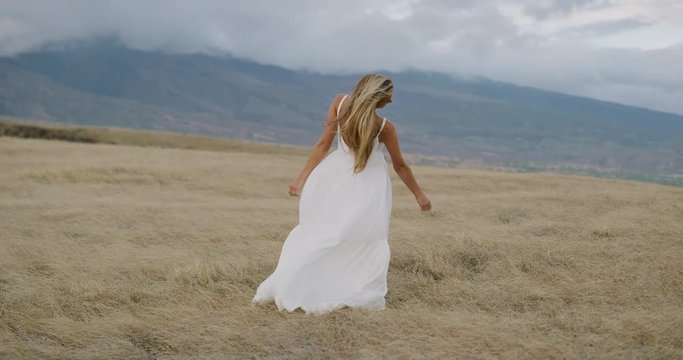Beautiful happy bride in her white dress opening her arms in joy with her hair blowing in the wind, bohemian woman