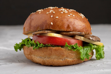 closeup of juicy fresh mushroom burger, tomato slice and salad leaves, marzipan cheese