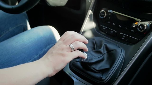 Closeup slow motion video of female driver shifting manual gears in car