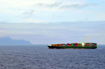 Container ship sailing near Japanese island Hokkaido during spring time.