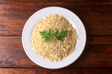 organic brown rice grain cooked in white dish on rustic wooden table. Integral rice