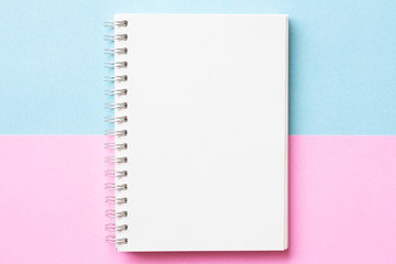 Flat lay of Notebook on pastel blue and pink color background, minimal style. Work space.