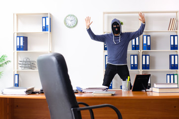 Male thief in balaclava in the office 