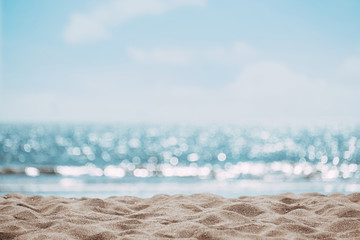 Fototapeta na wymiar Seascape abstract beach background. blur bokeh light of calm sea and sky. Focus on sand foreground.
