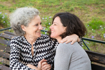 Cheerful happy senior lady embracing adult daughter outdoors. Young woman sharing good news with...