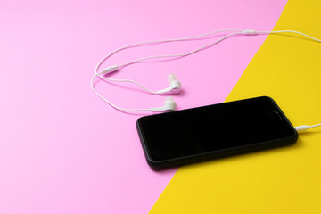 Smartphones and headphones Listen to vintage music on a yellow and pink background.